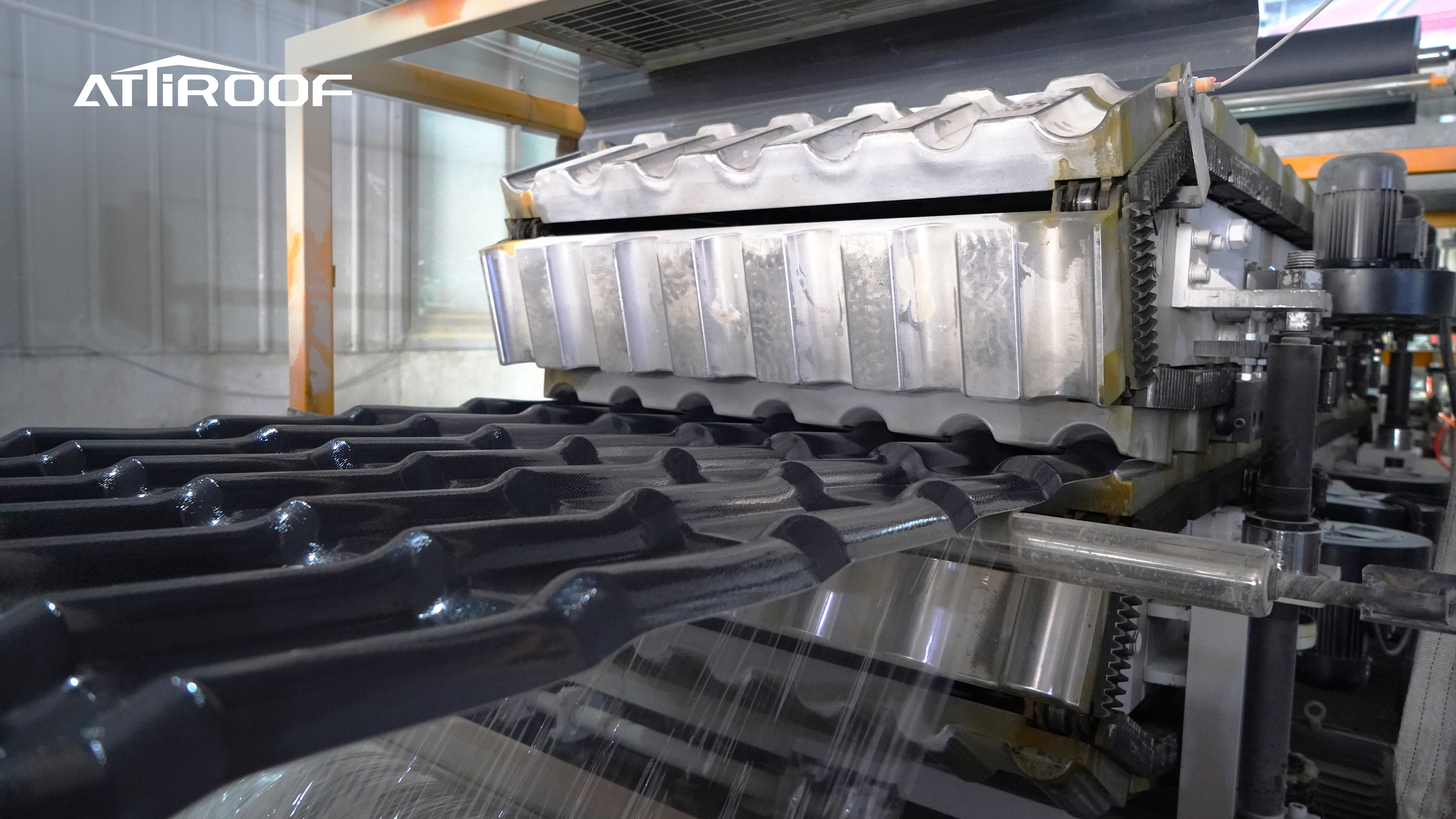 Processo de fabricação das telhas de resina sintética preta com logo ATiROOF, mostrando a linha de produção e maquinários em operação. Processo de fabricação das telhas de resina sintética preta com logo ATiROOF, mostrando a linha de produção e maquinários em operação.