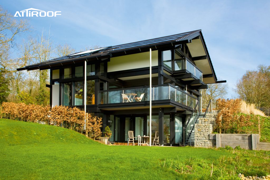 Uma casa moderna e ecológica recém-construída, com grandes janelas de vidro e um elegante telhado de resina sintética preta, em meio a uma paisagem natural. Uma casa moderna e ecológica recém-construída, com grandes janelas de vidro e um elegante telhado de resina sintética preta, em meio a uma paisagem natural.